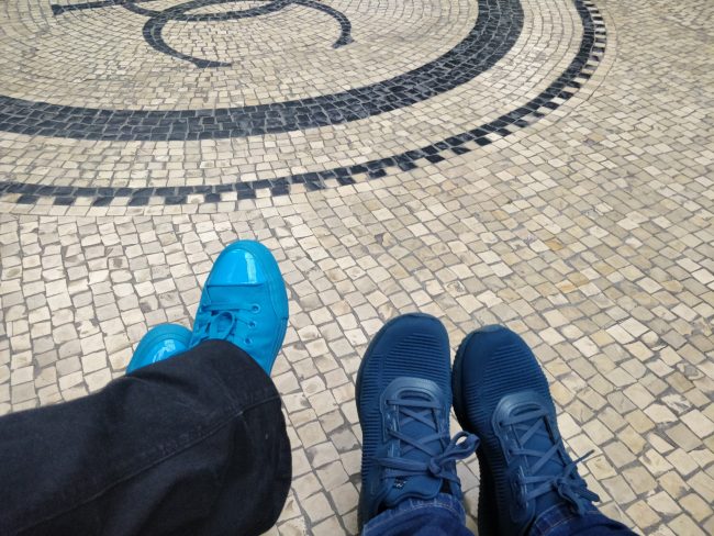 To personer sidder på en bænk på Glyptoteket, begge iført blå sko.