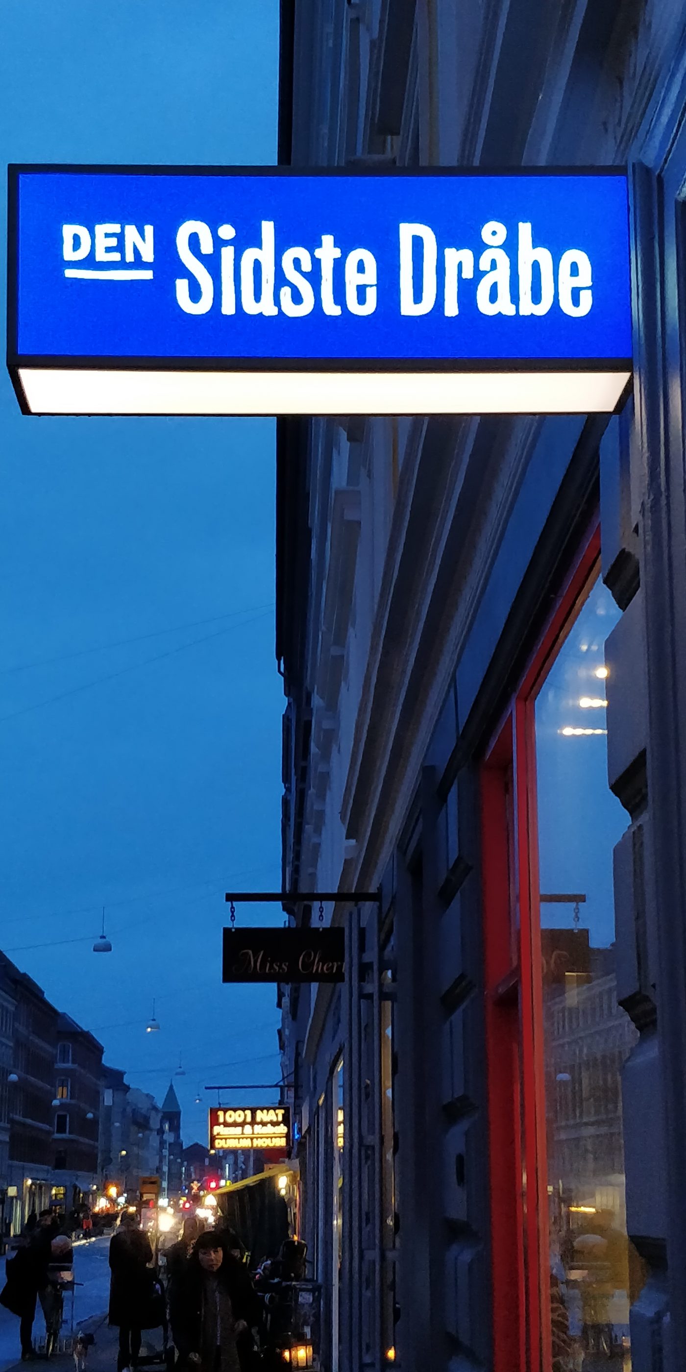 Blå aftenhimmel over Istedgade, Købehavn. Et skilt med teksten "Den sidste dråbe".