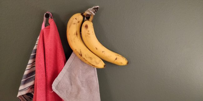 Et par knager, hvor der hænger et håndklæde, et viskestykke samt to bananer.
