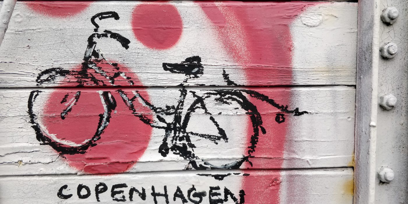 Street art: a black bicycle on a white and pink background, Copenhagen.